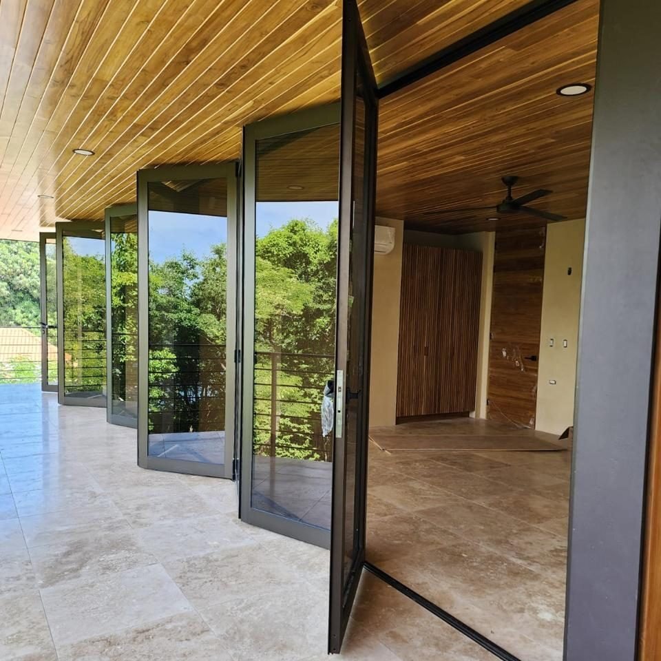 Puertas plegables de vidrio abiertas hacia una terraza con cielo de madera