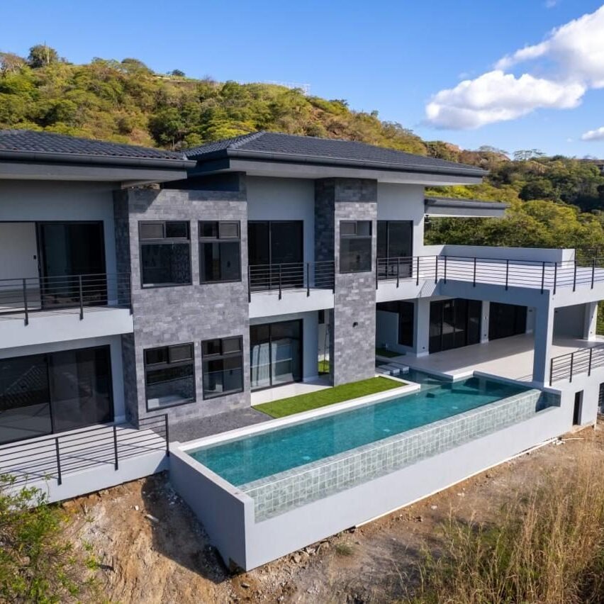 Casa en una ladera con piscina infinita y ventanería de perfil negro