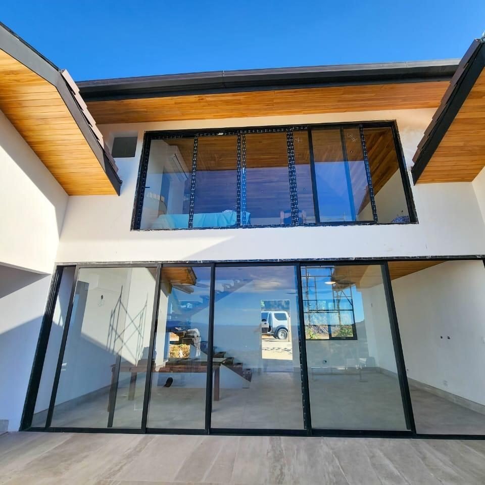 Fachada con ventanal y puertas corredizas de piso a techo de perfil negro