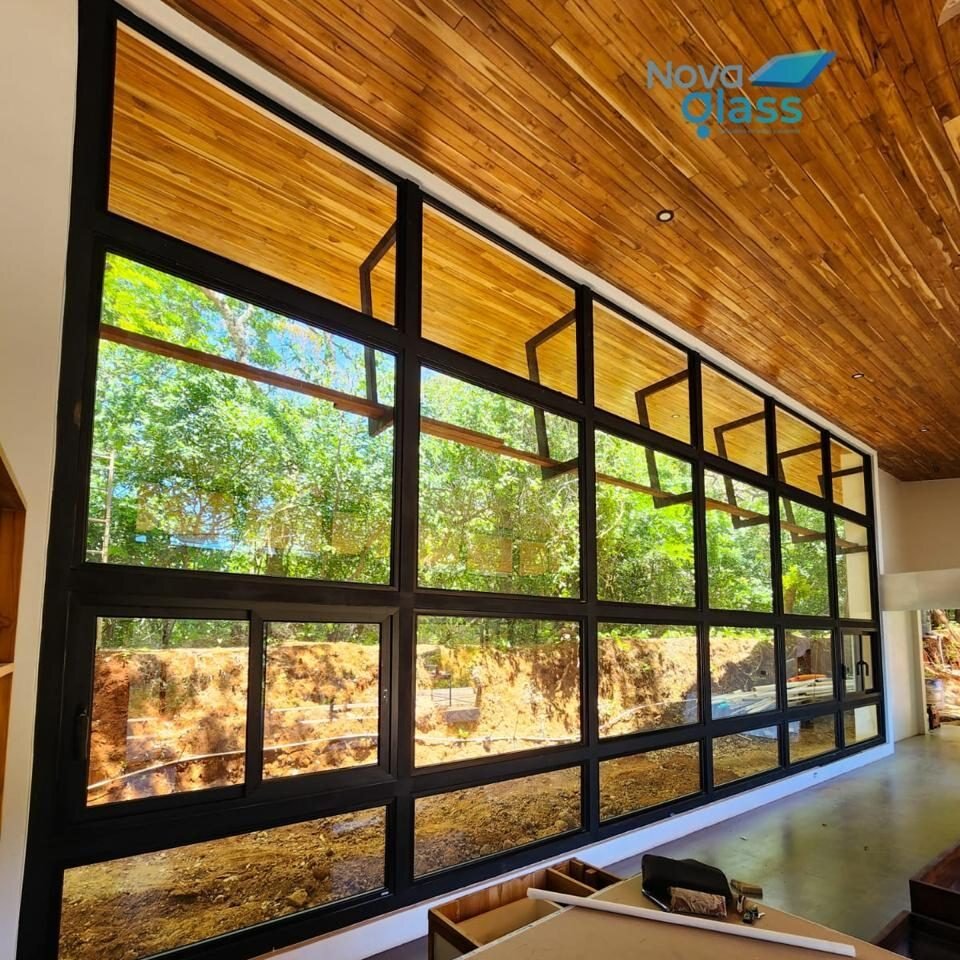 Muro de ventanas de perfil negro bajo un cielo de madera