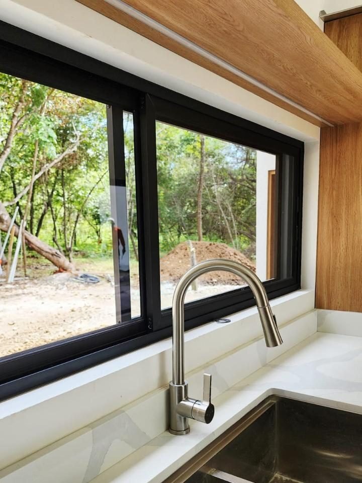 Ventana corrediza de perfil negro sobre el fregadero de una cocina