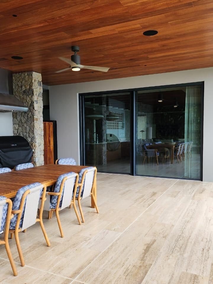 Terraza techada con puerta corrediza de perfil negro hacia el comedor